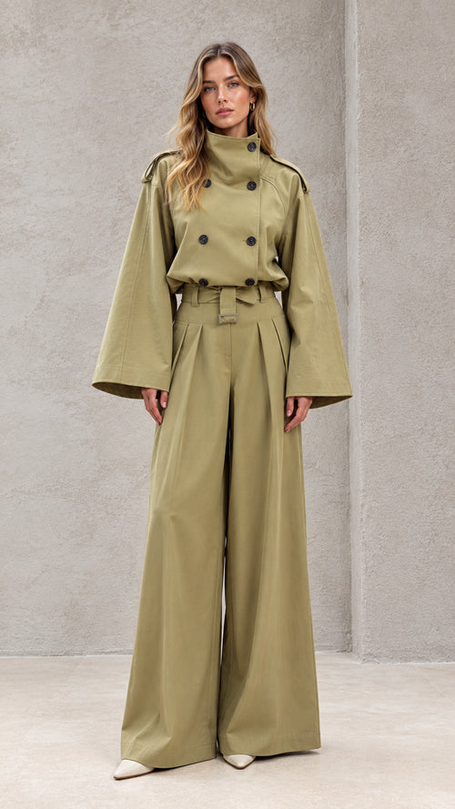Front full-length view of model wearing sage green double-breasted wide-leg trench jumpsuit