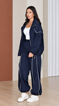 Front view of woman wearing navy blue 2-piece windbreaker tracksuit set with white contrast piping