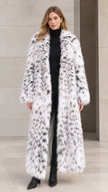 Front full view of woman wearing full-length white speckled faux fur maxi coat with black turtleneck and boots