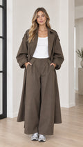 Model wearing oversized olive brown maxi trench coat and matching wide-leg trousers front view