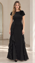 Front view of black short sleeve maxi evening dress with floral shoulder appliqué and cascading side ruffles