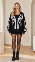 Front view of model wearing black oversized skeleton graphic knit cardigan with combat boots