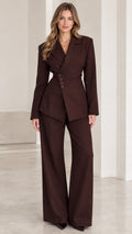 Front view of woman wearing chocolate brown asymmetric button blazer and wide leg trousers