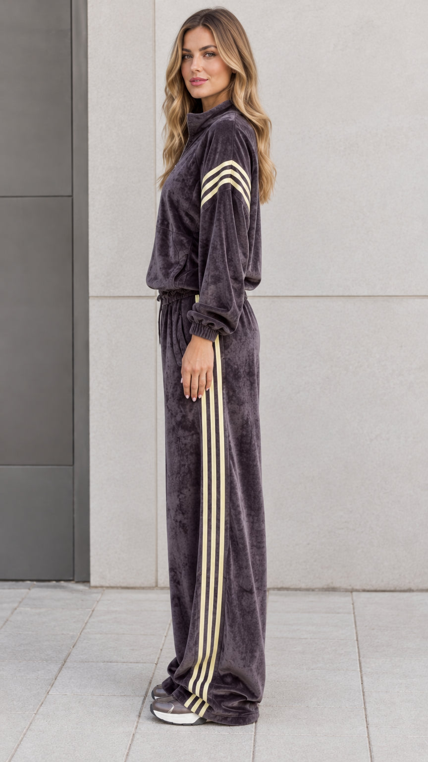 Side profile view of model in charcoal grey plush velour tracksuit showing contrast side stripes