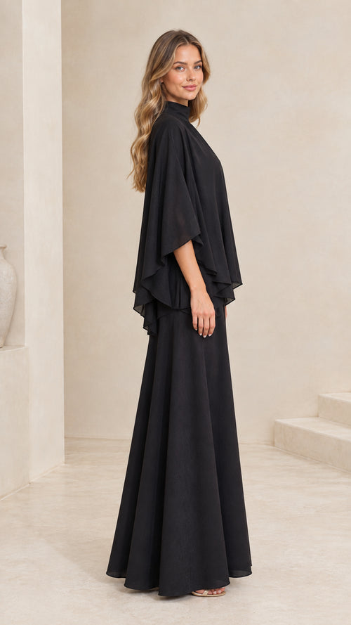 Side profile of woman in flowing black tiered cape maxi gown