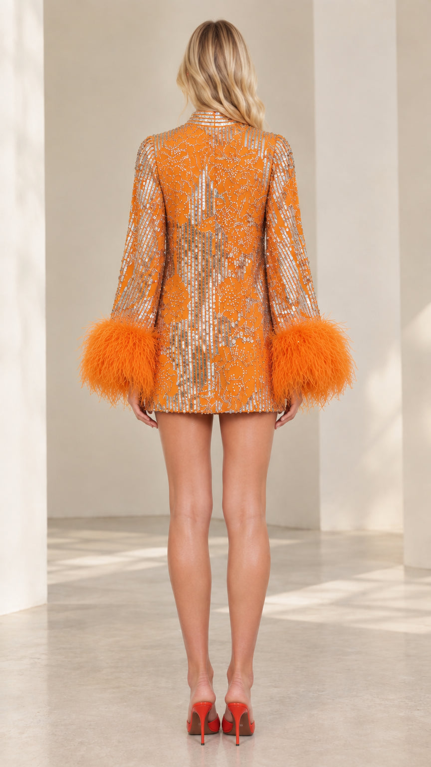 Back view of model in orange sparkly sequin dress with long feather cuff sleeves