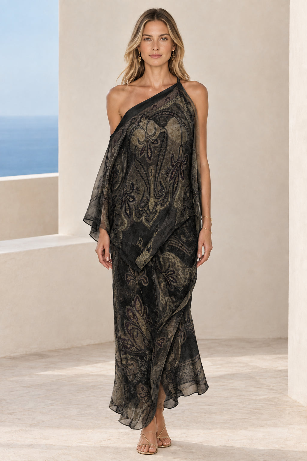 Front view of woman wearing black paisley print one-shoulder draped maxi dress
