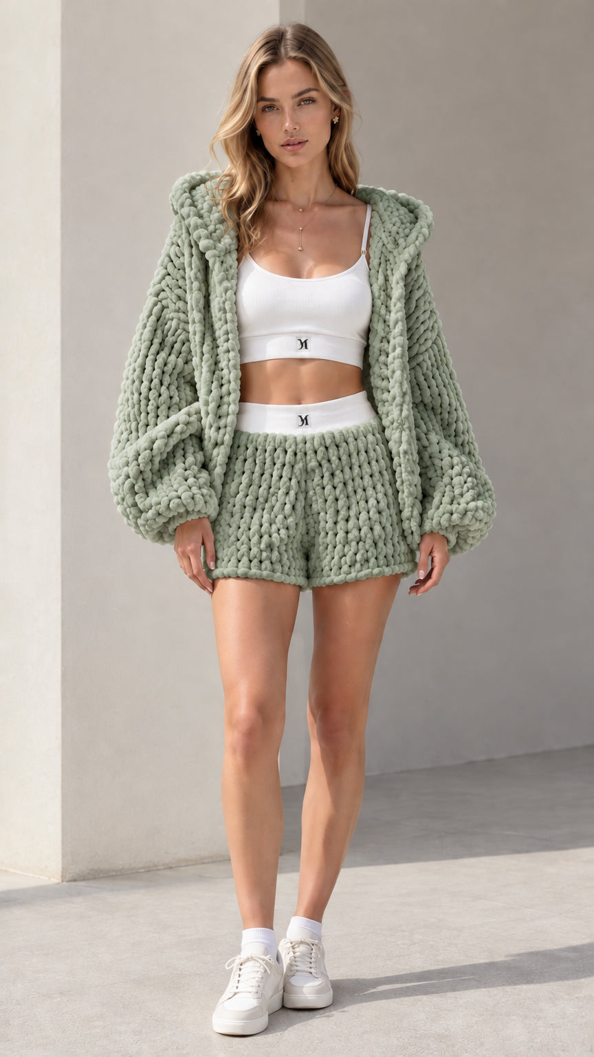 Model wearing sage green chunky knit hooded cardigan and matching shorts set